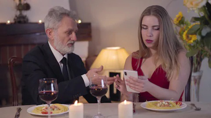 An older man is exchanging number with a young woman